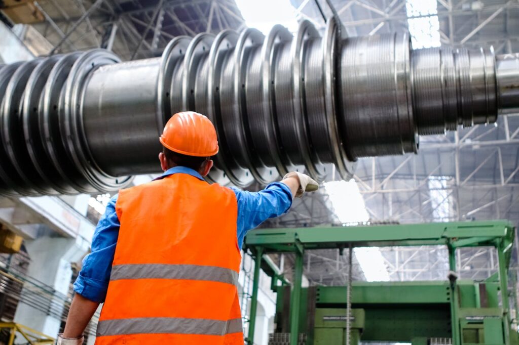 pexels photo 2760241 Engineer in high visibility vest and hard hat inspecting large machinery in factory setting.