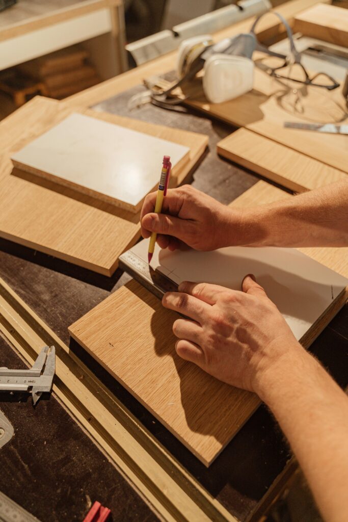 pexels photo 5466151 5466151 A skilled woodworker measuring wood pieces in an indoor workshop.
