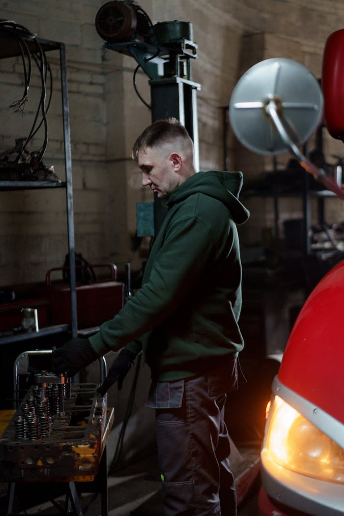 services-01 A focused mechanic working on automotive repair in a dimly lit garage setting.