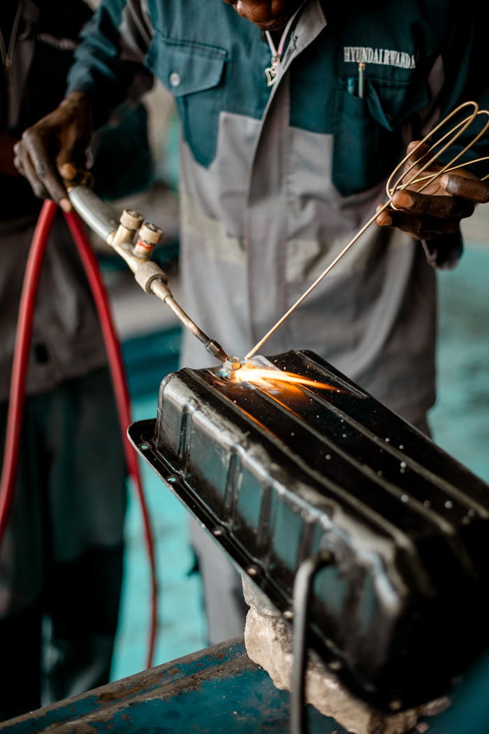 Close-up of a welder using a torch on metalwork in an industrial workshop setting.